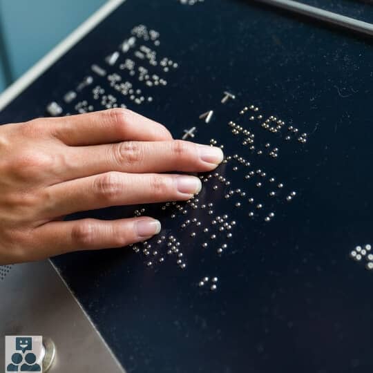Braille, een hand betast een zwart bord met braille schrift.