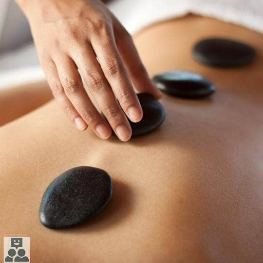 Massagetherapie, warme zwarte stenen worden op een rug gelegd.